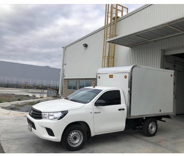 Camioneta con caja cerrada frente a una bodega